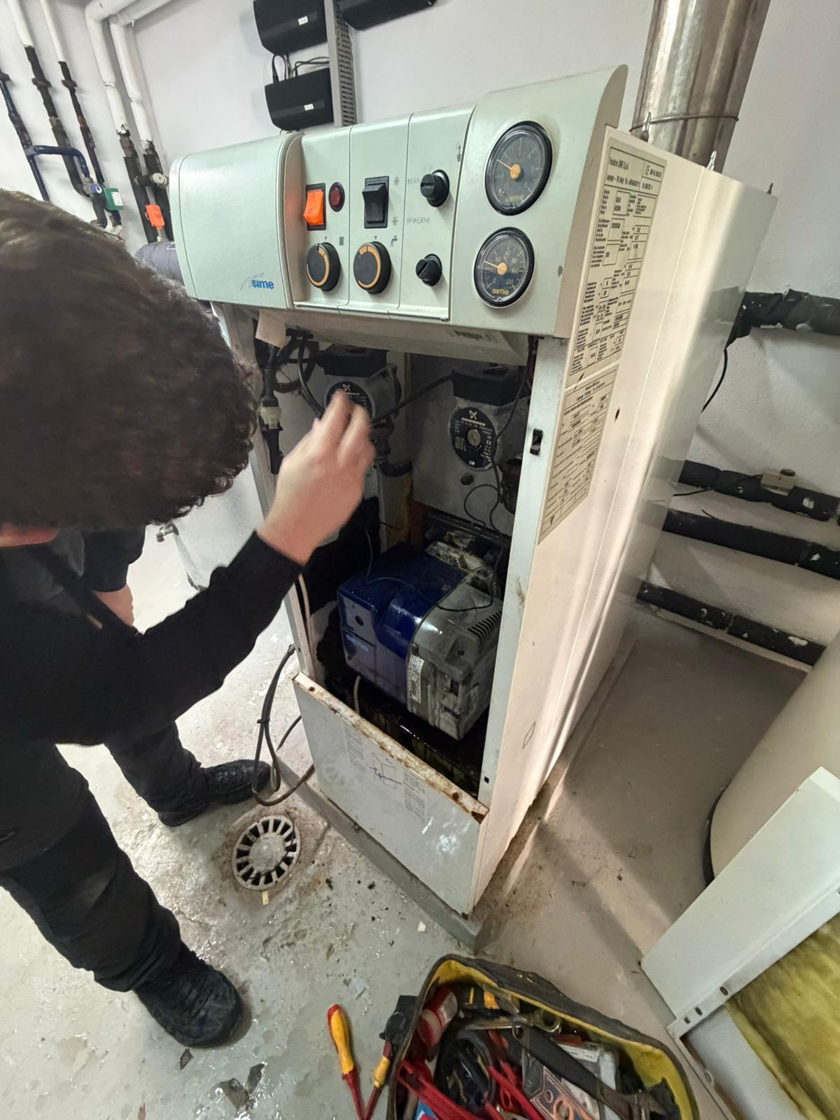 Technician inspecting inside Sime oil boiler with Grundfos circulation pumps