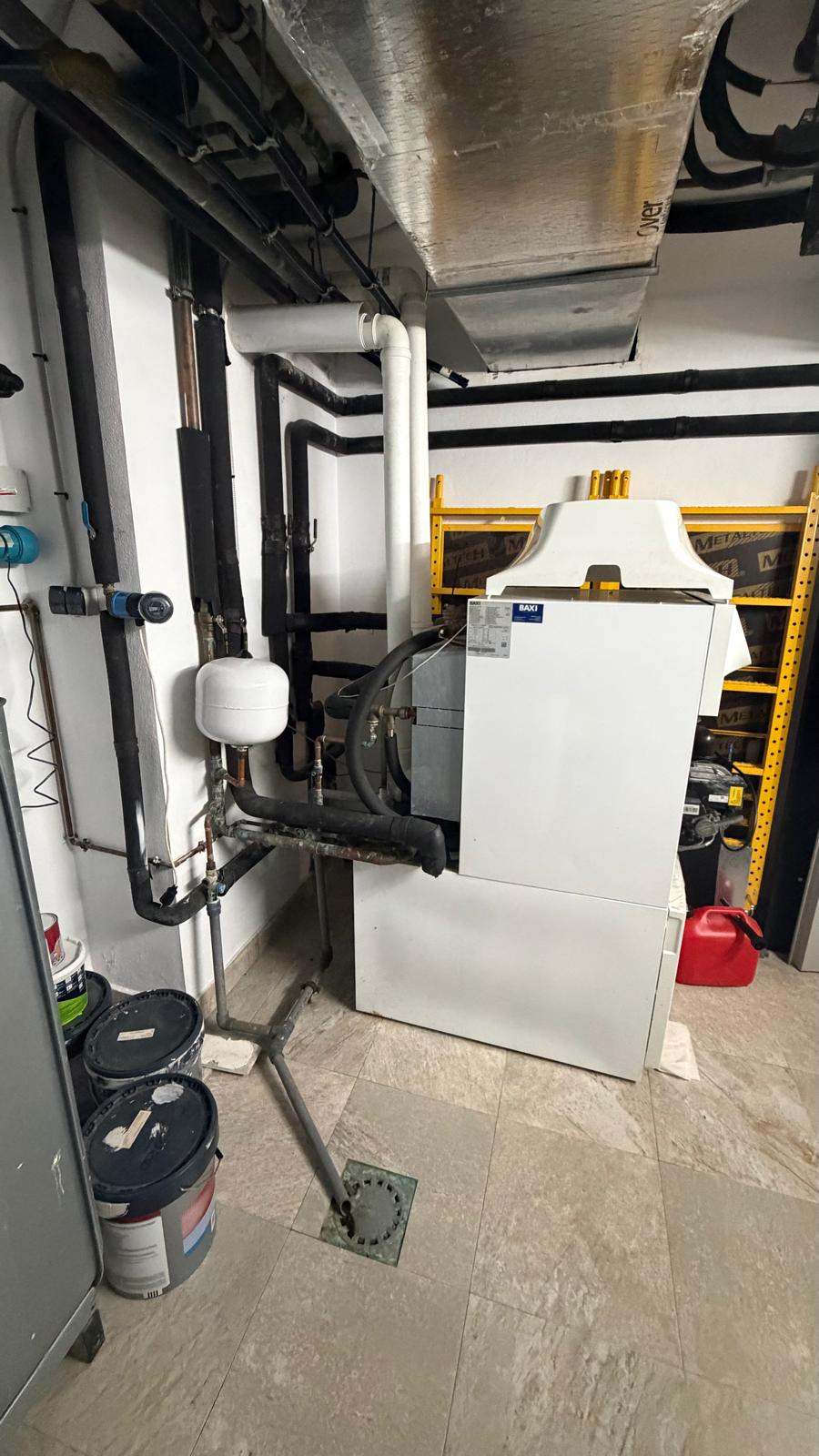 Baxi boiler with new black insulated pipework already being routed alongside it — start of decommissioning process in La Cala de Mijas
