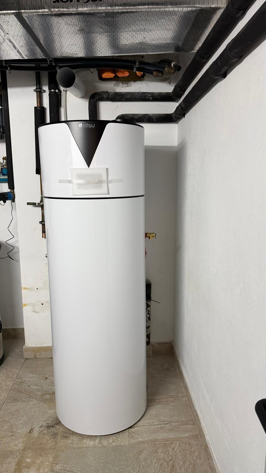 Close-up view of Daitsu aerothermal heat pump installed in La Cala de Mijas plant room — Daitsu brand logo visible on top unit, black insulated overhead pipework and hydraulic manifold to left