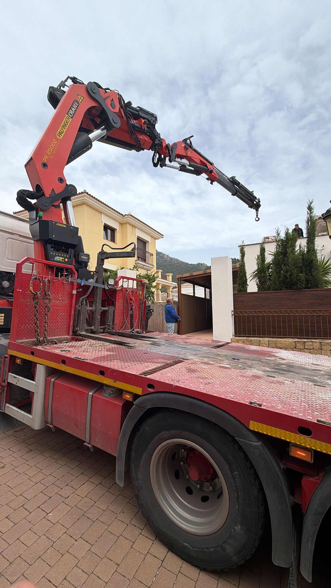 Close-up detail of Palfinger crane with red flatbed truck during heat pump installation at La Cala de Mijas — specialist crane equipment for rooftop HVAC deliveries on the Costa del Sol