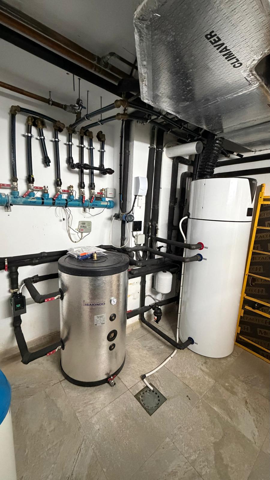 La Cala de Mijas villa plant room fully installed — Ibaiondo buffer and Daitsu aerothermal installed, hydraulic manifold, red expansion vessel and water softener visible, complete Agua Therm heat pump system