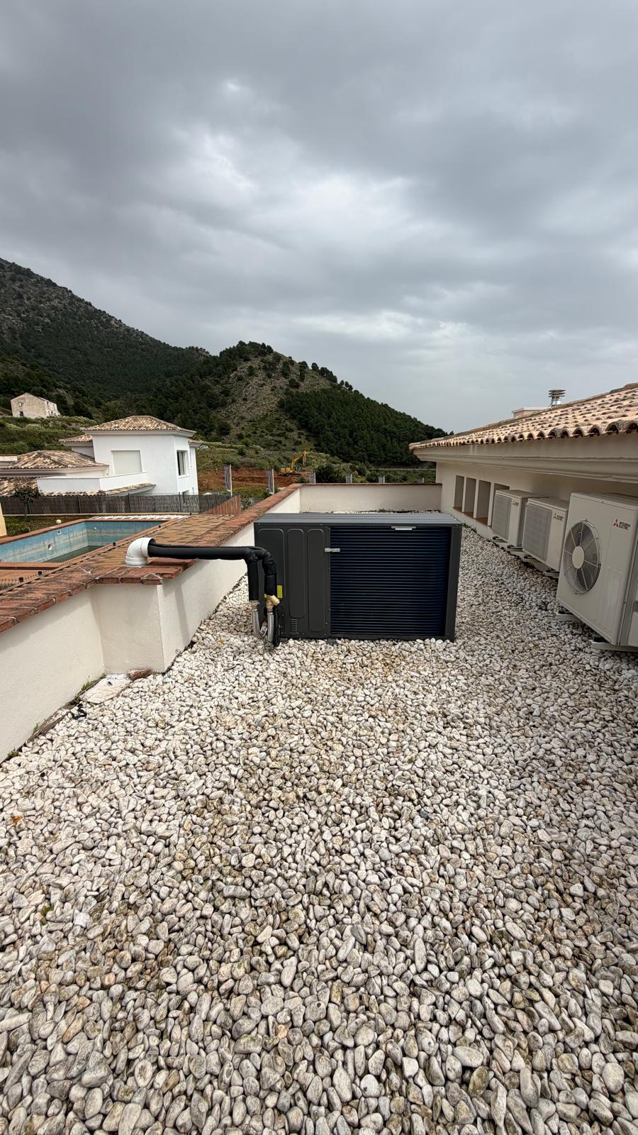 Wide panoramic view of La Cala de Mijas villa rooftop with Midea heat pump outdoor unit installed — pool, Sierra de Mijas mountains and existing Mitsubishi outdoor units visible in background