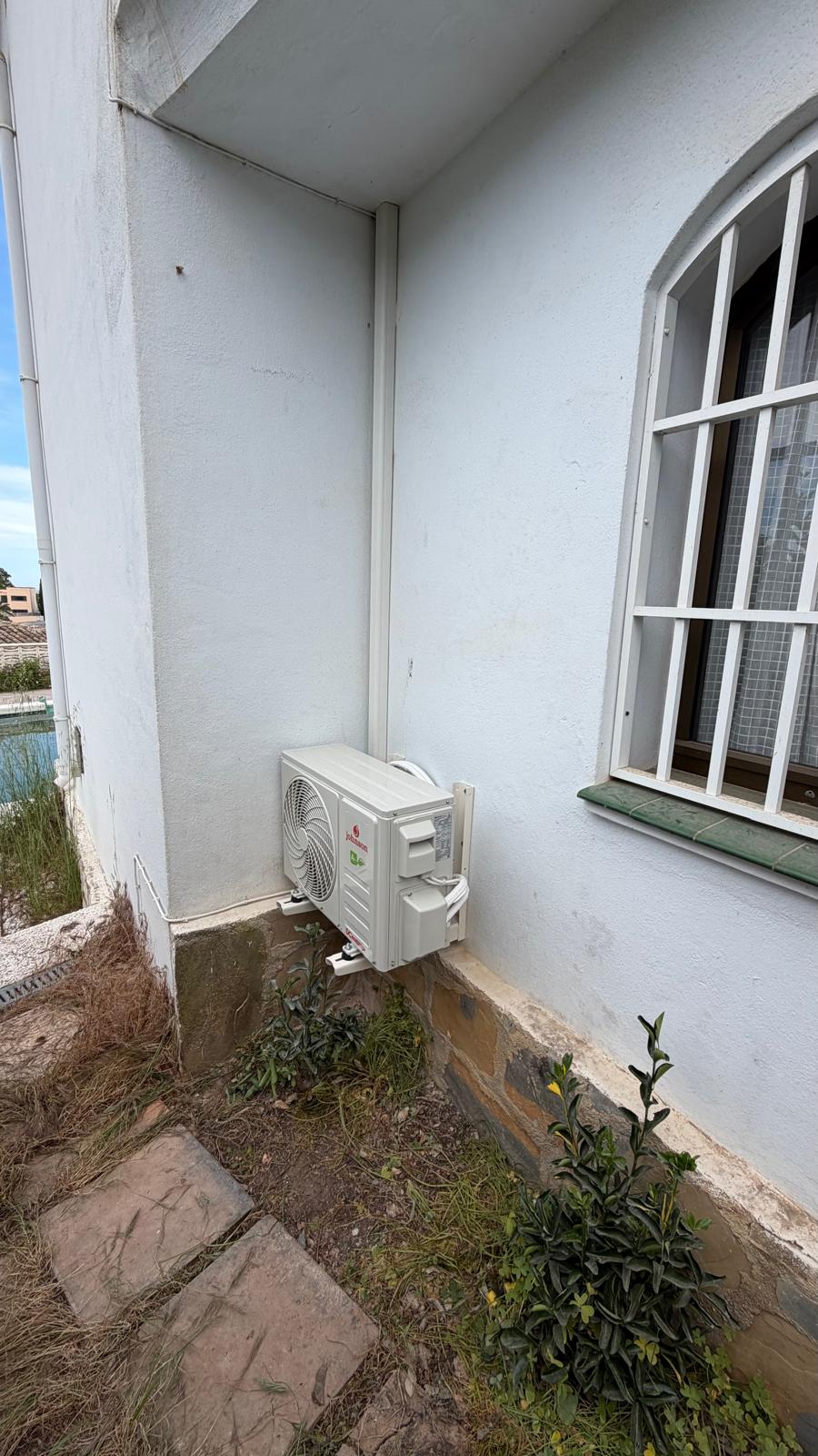 Unidad exterior Johnson posicionada en lateral de fachada blanca con holgura para servicio