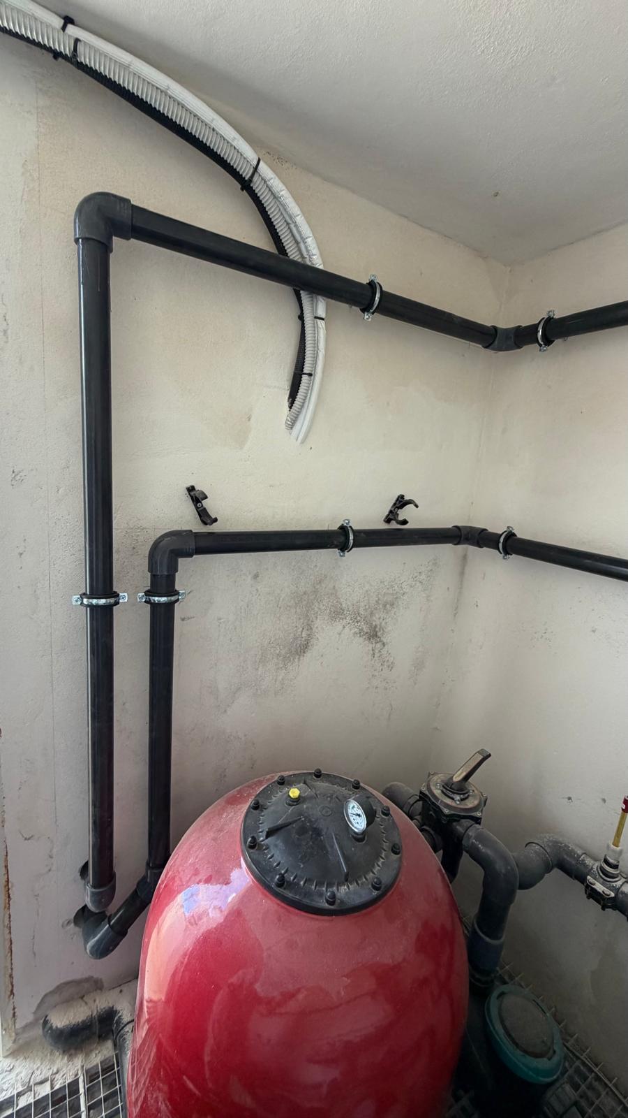 Black PVC return lines clipped to wall with saddle straps and conduit