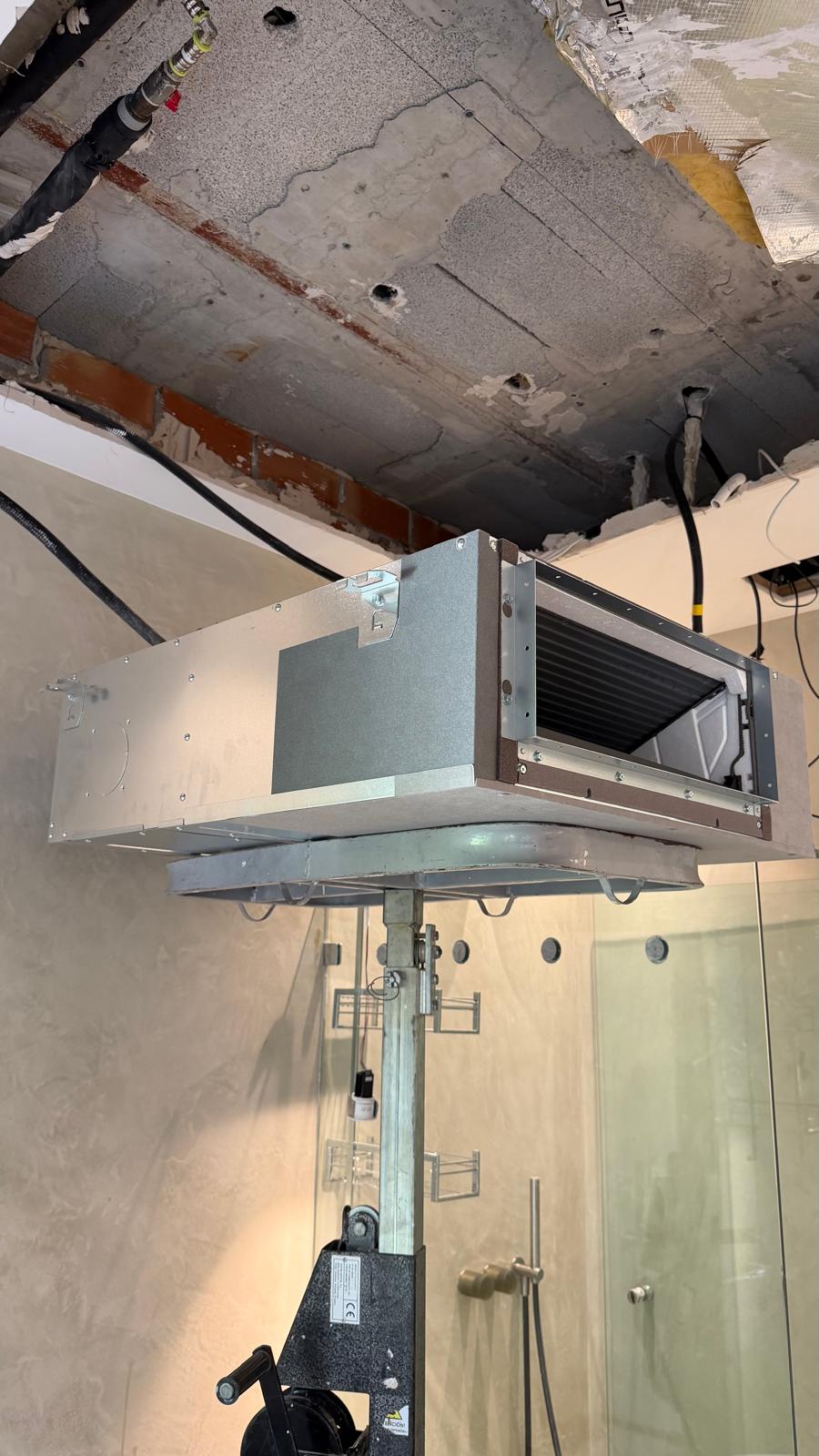 Unidad interior Daikin por conductos oculta colgada en plenum sobre varilla roscada — baño de villa San Pedro