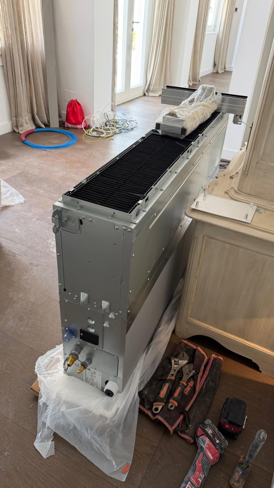 Unidad interior Daikin grande por conductos en el suelo antes de colgar — batería visible