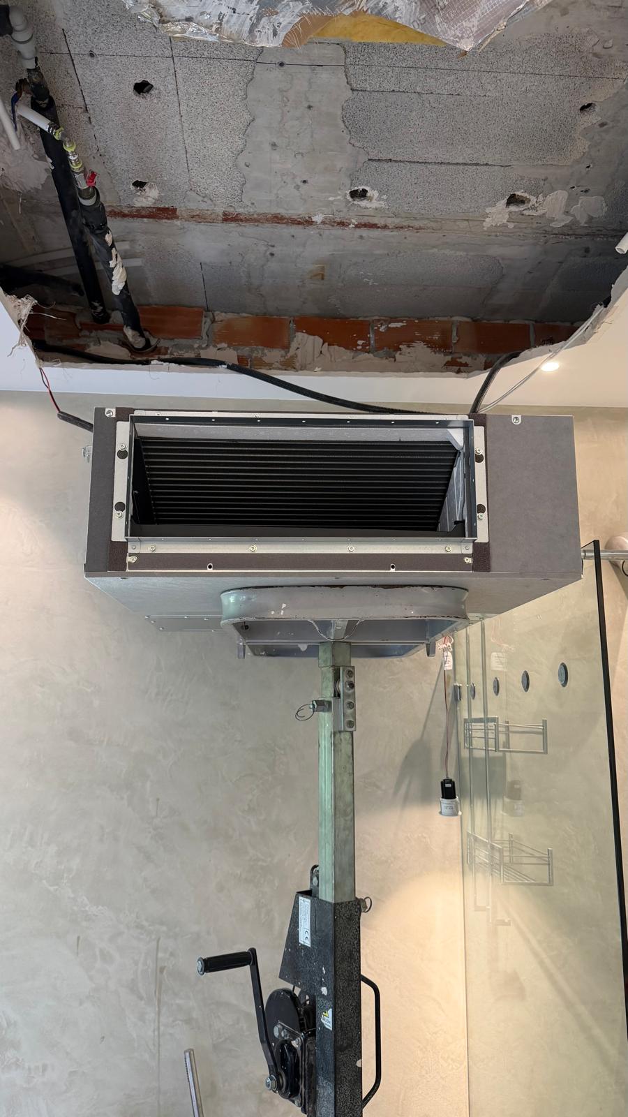 Unidad interior Daikin por conductos finalmente colgada en plenum del baño — vista frontal