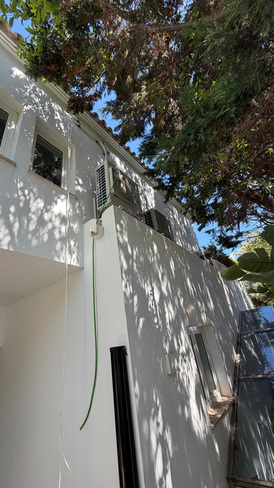 Dos unidades exteriores Daikin en terraza superior con línea frigorífica subiendo limpiamente por pared blanca enfoscada — villa San Pedro