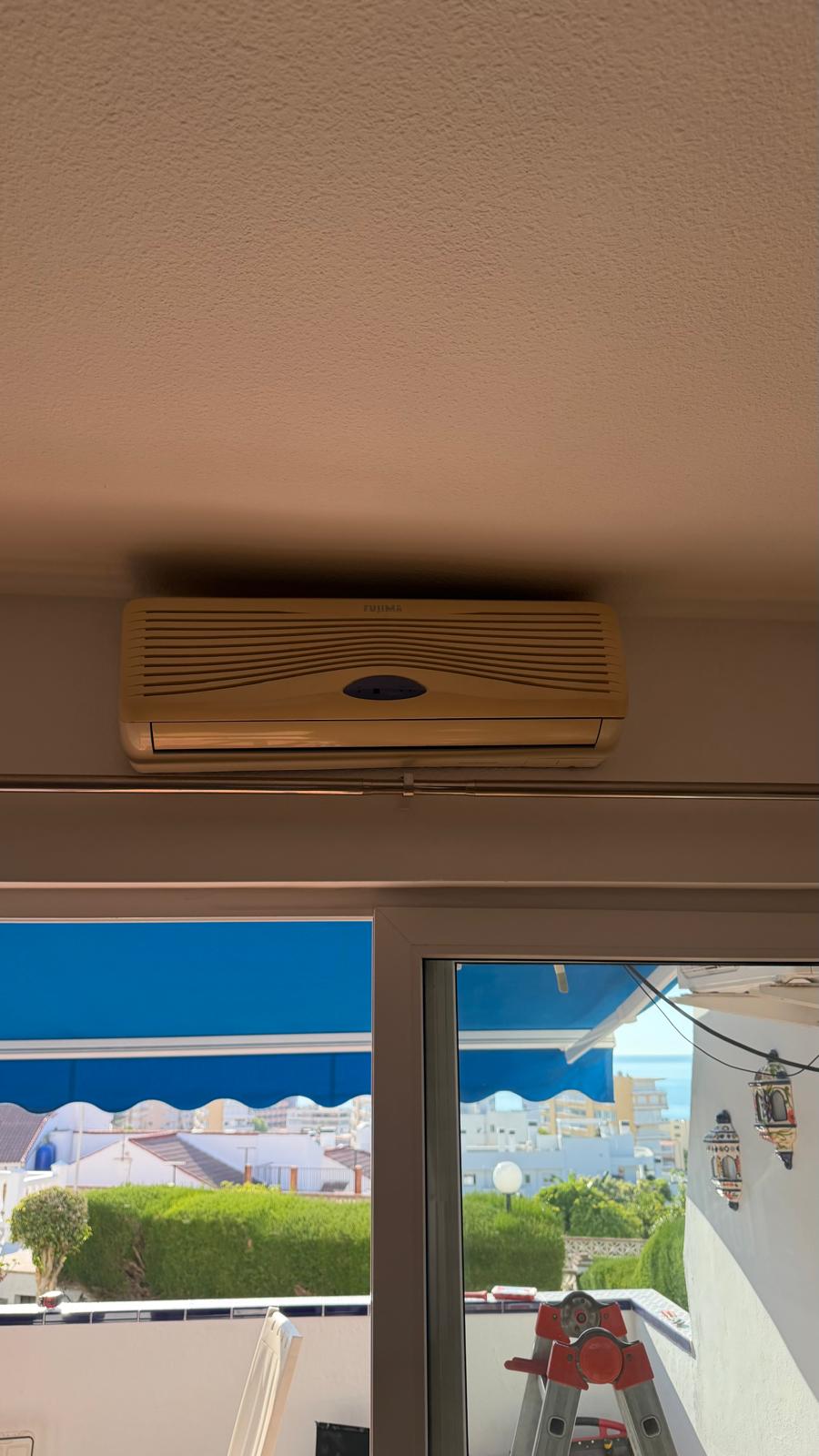 Old Fujitsu outdoor AC unit showing dirty grilles and rusty mounting brackets before removal