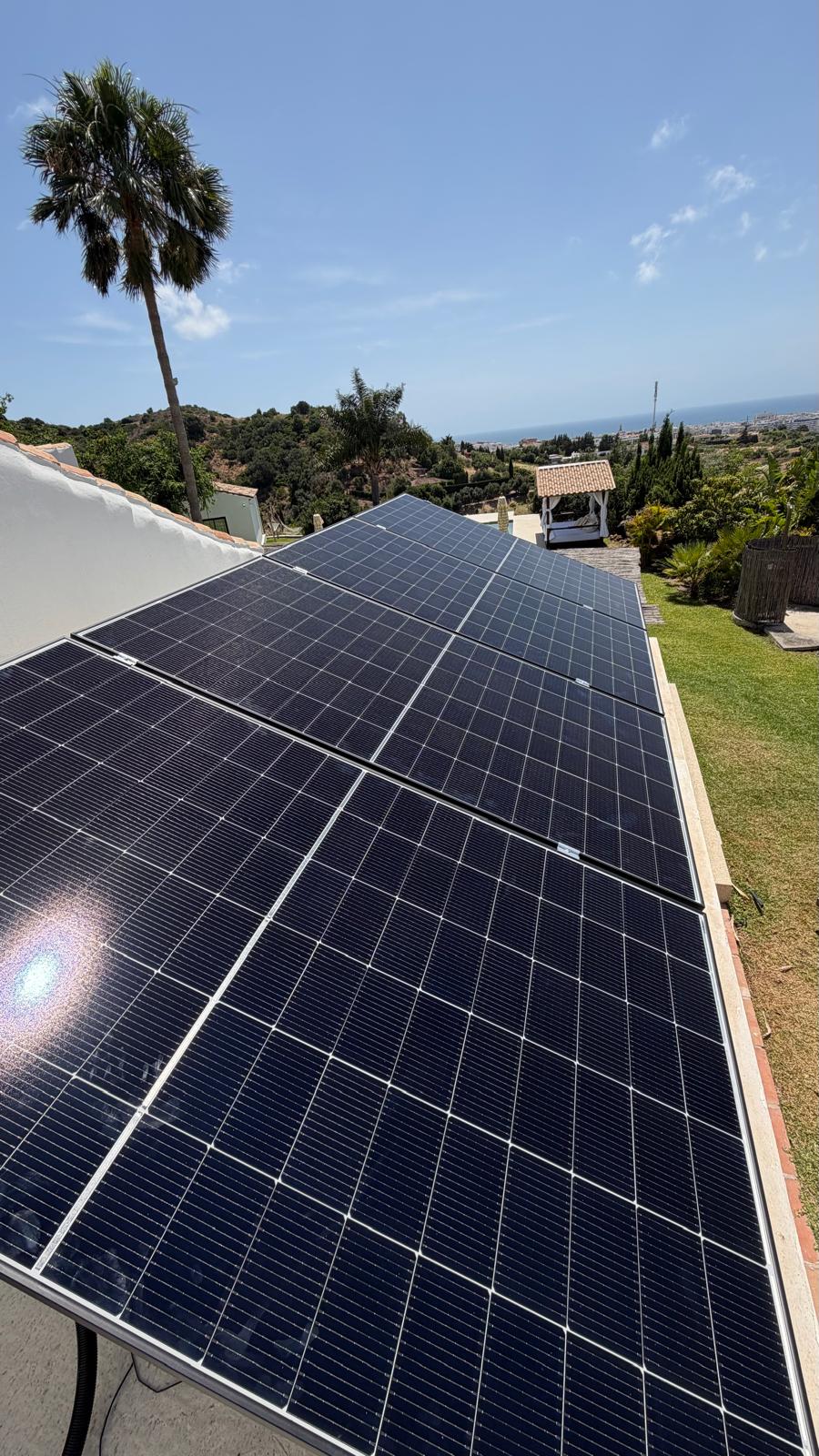 Paneles solares monocristalinos en la cubierta de teja de la villa, con el Mediterráneo en el horizonte — San Pedro de Alcántara, Marbella.